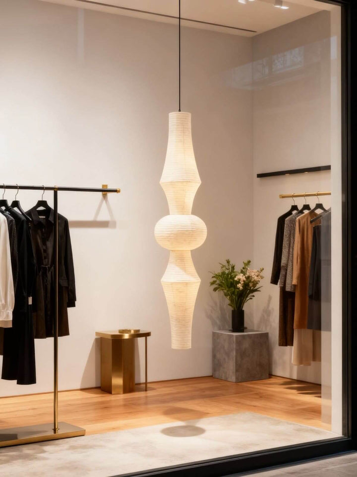 Washi paper pendant light glowing inside a minimalist clothing boutique with open display rails