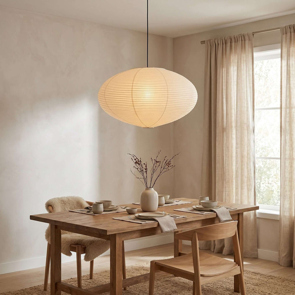 Washi paper pendant light glowing above a wood dining table.