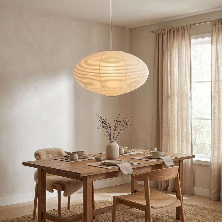 Washi paper pendant light glowing above a wood dining table.