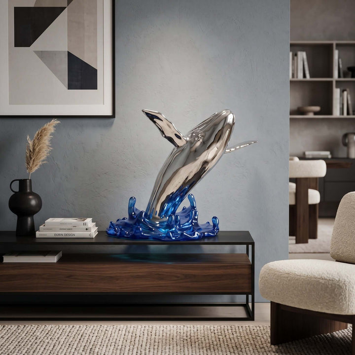 Silver and blue whale sculpture displayed on a low cabinet in a modern neutral living room.