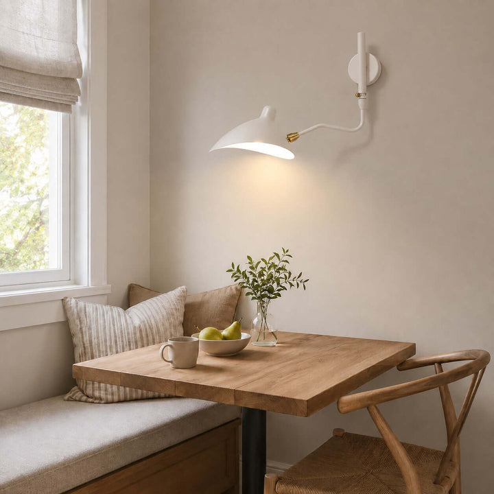 White one-light swing arm wall light above a breakfast nook table