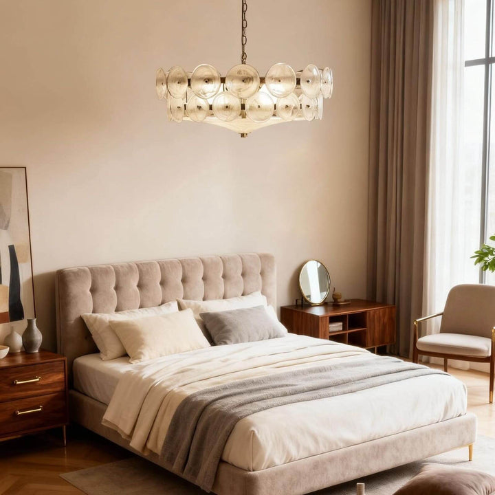 White glass bedroom chandelier with round discs above an upholstered bed