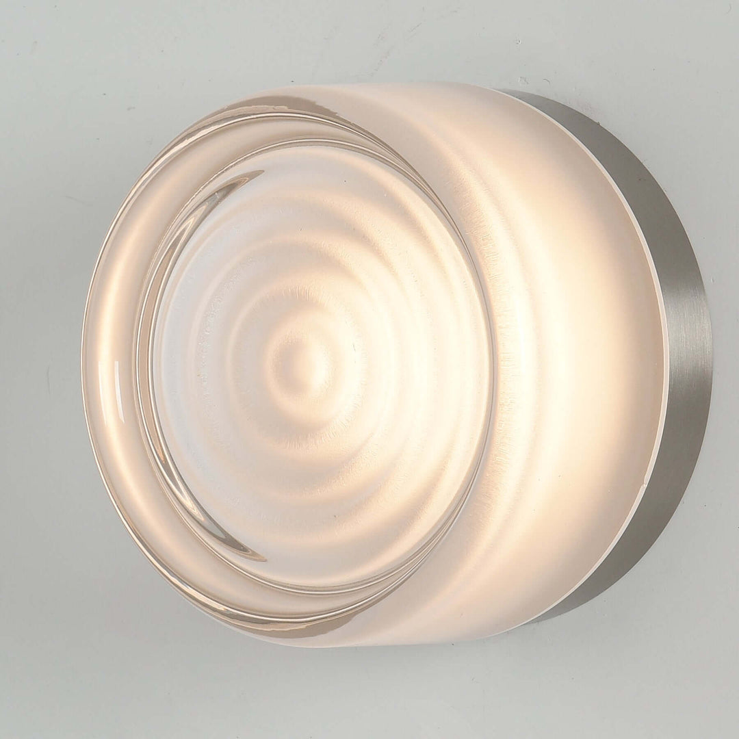 White glass Dimple wall sconce shown from the side on a gray wall.