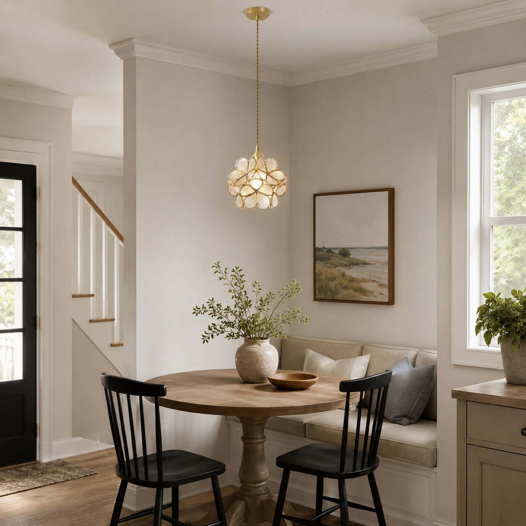 White glass petal pendant light above a round dining table near a built-in bench