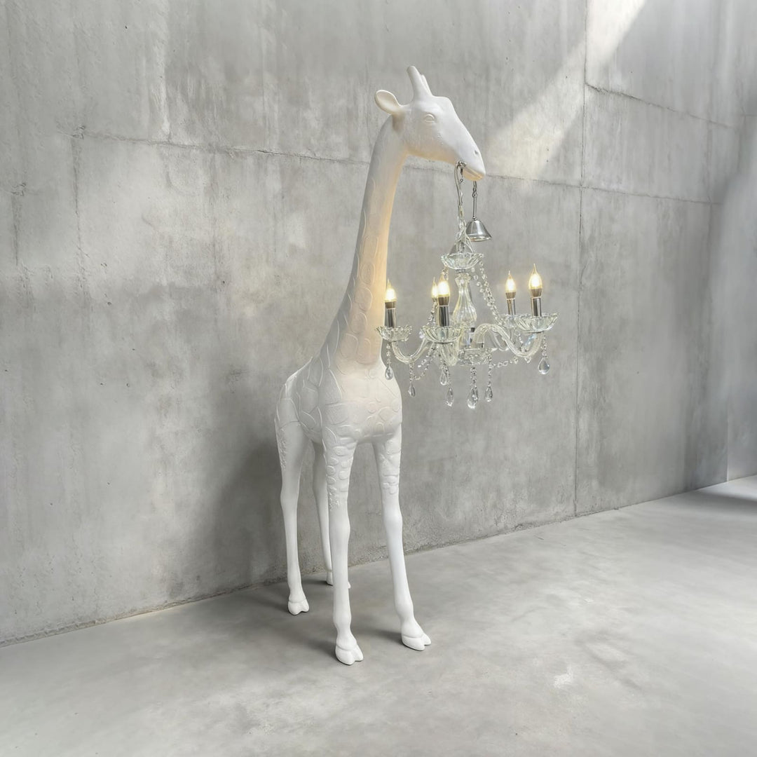 White and silver giraffe floor lamp with a crystal chandelier against a concrete wall
