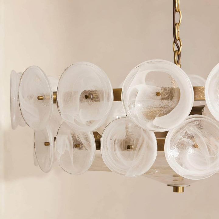 Close-up of white swirled glass discs attached to a brass-tone chandelier frame