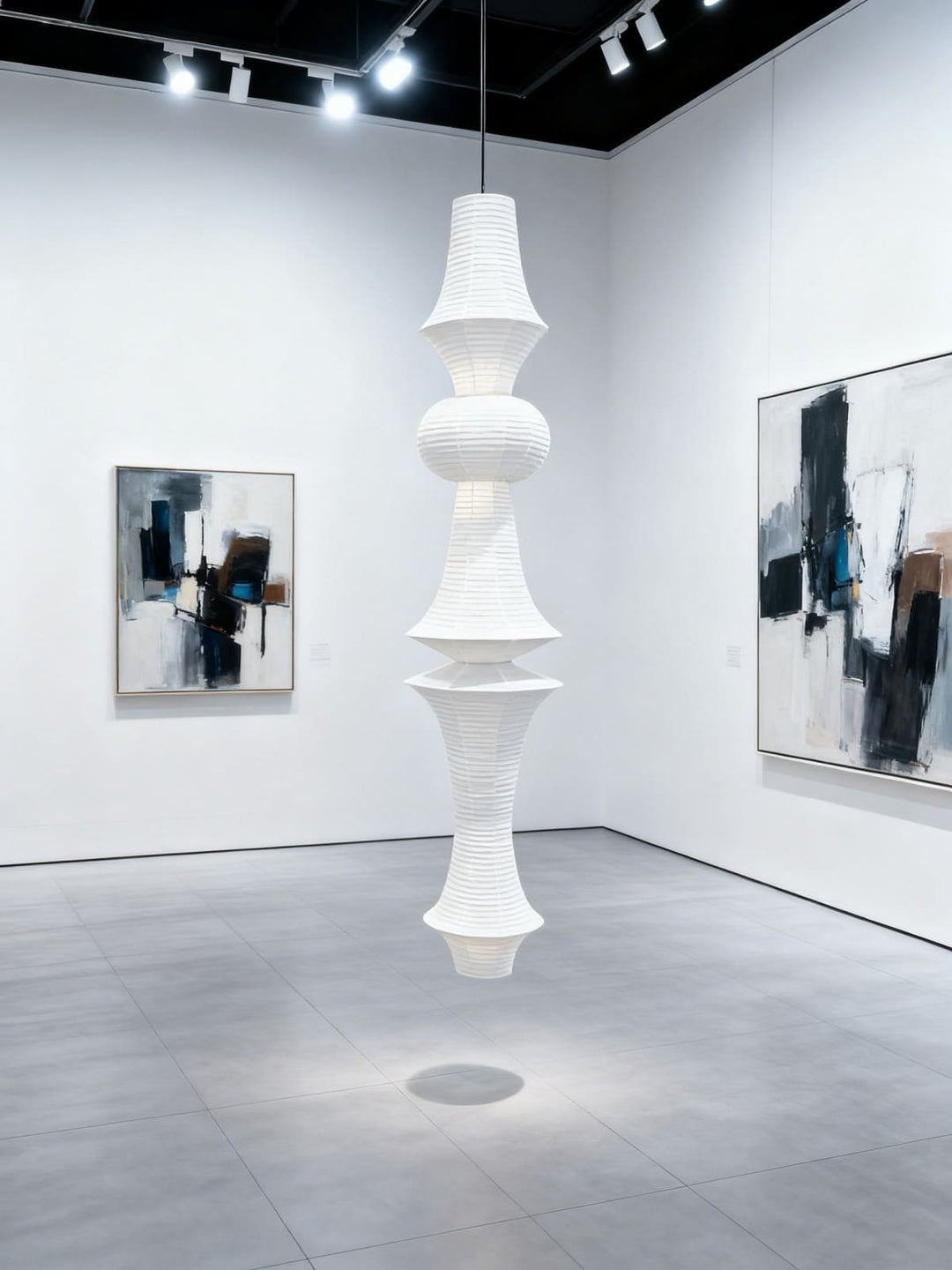 Tall white Washi paper pendant light displayed in a contemporary art gallery with abstract paintings