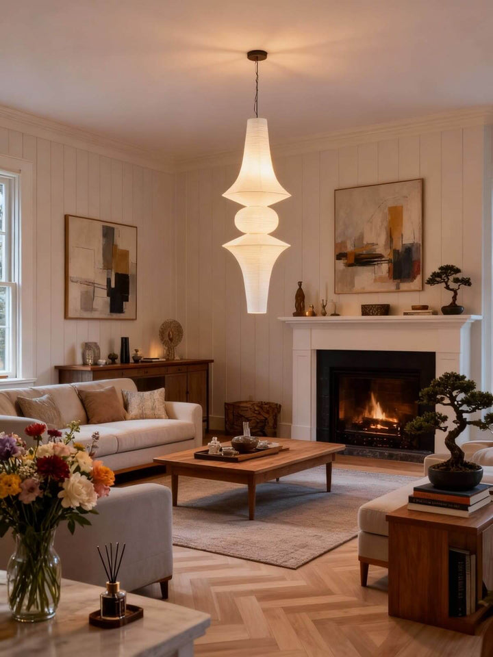 White Washi paper pendant light suspended above a neutral living room with a fireplace and wood coffee table
