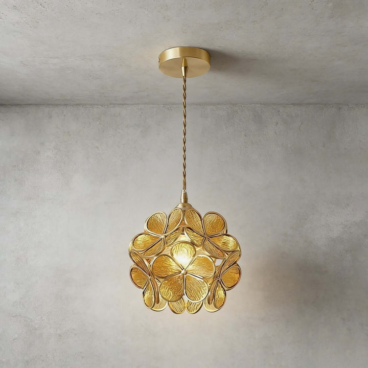 Yellow textured glass petal pendant light glowing warmly against a concrete wall