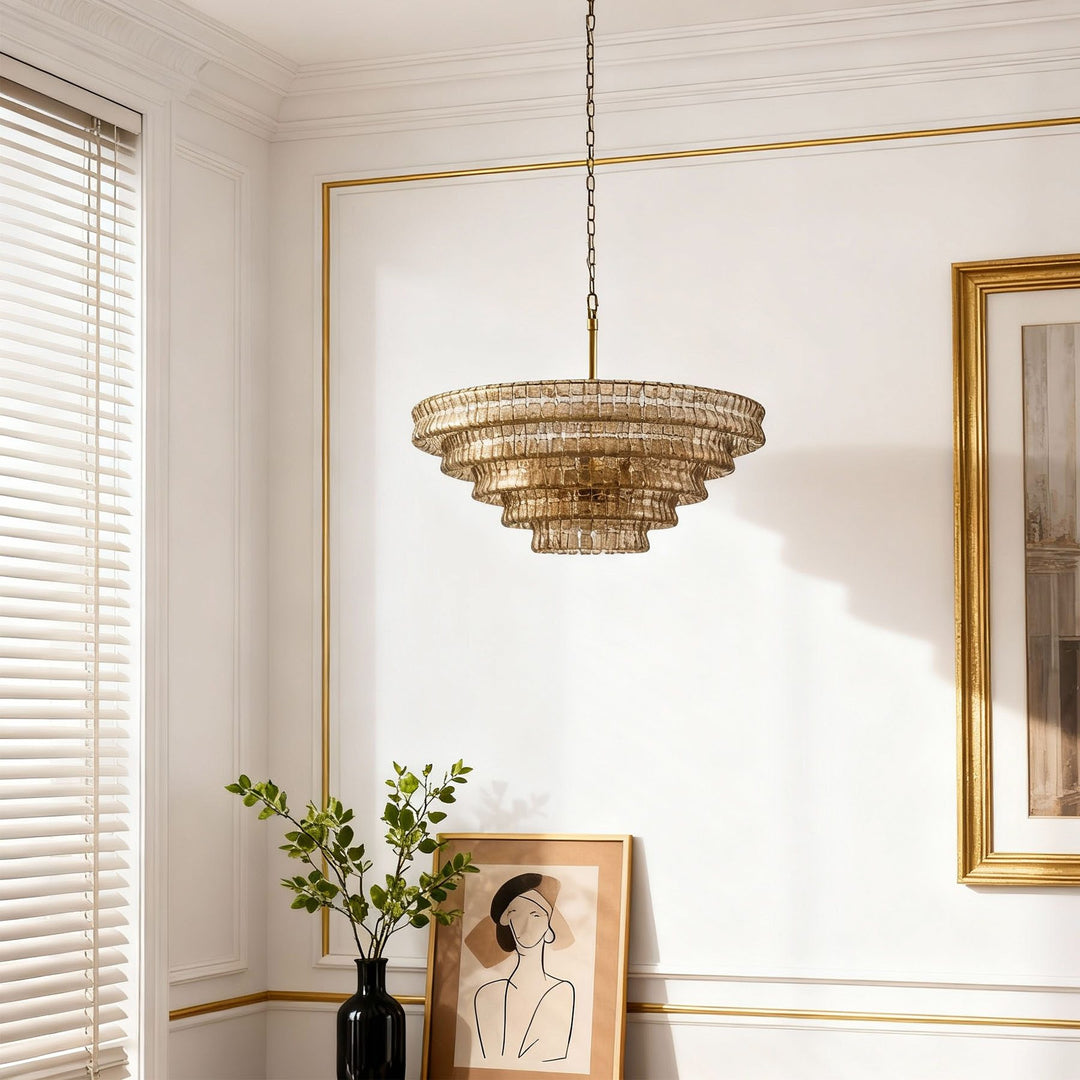 Smoky tiered glass chandelier on a gold trimmed wall with blinds and framed art