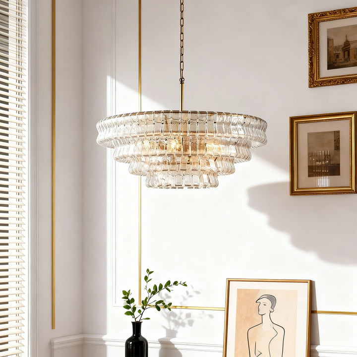 Clear glass chandelier glowing near a white wall with blinds and gold framed art