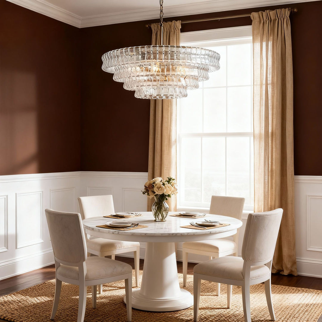 Clear glass chandelier over a round dining table with brown walls and beige curtains