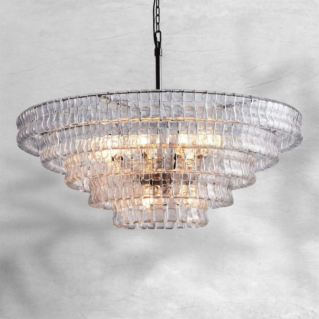 Wide clear glass chandelier with a black stem and warm bulbs on a gray background