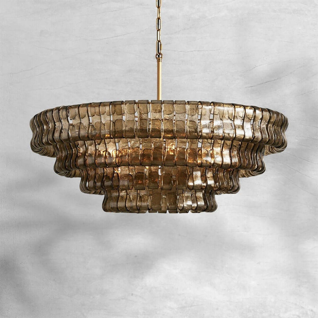 Smoky round glass chandelier with a gold chain and warm bulbs on a gray background