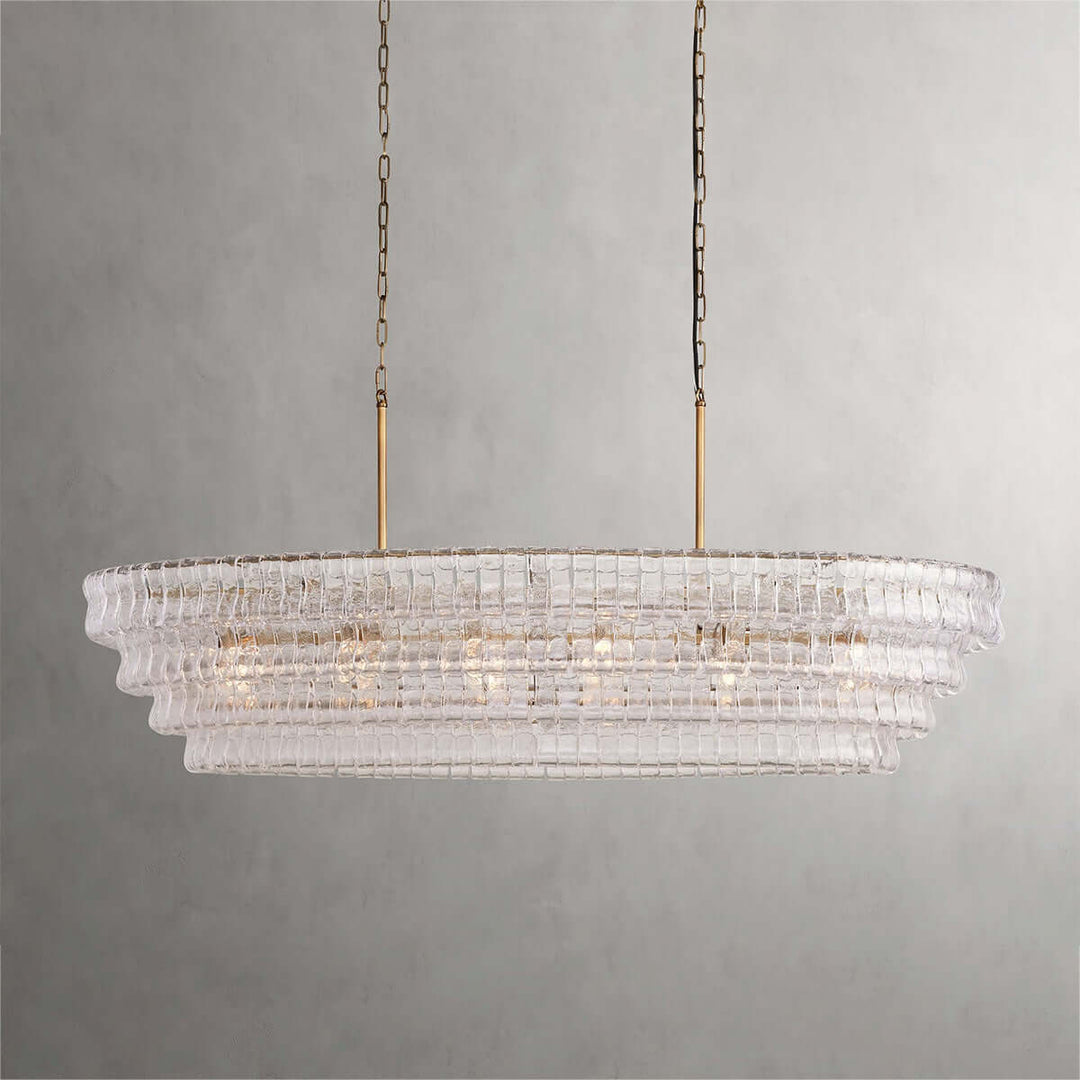 Close front view of a linear clear glass chandelier with gold chains and warm bulbs