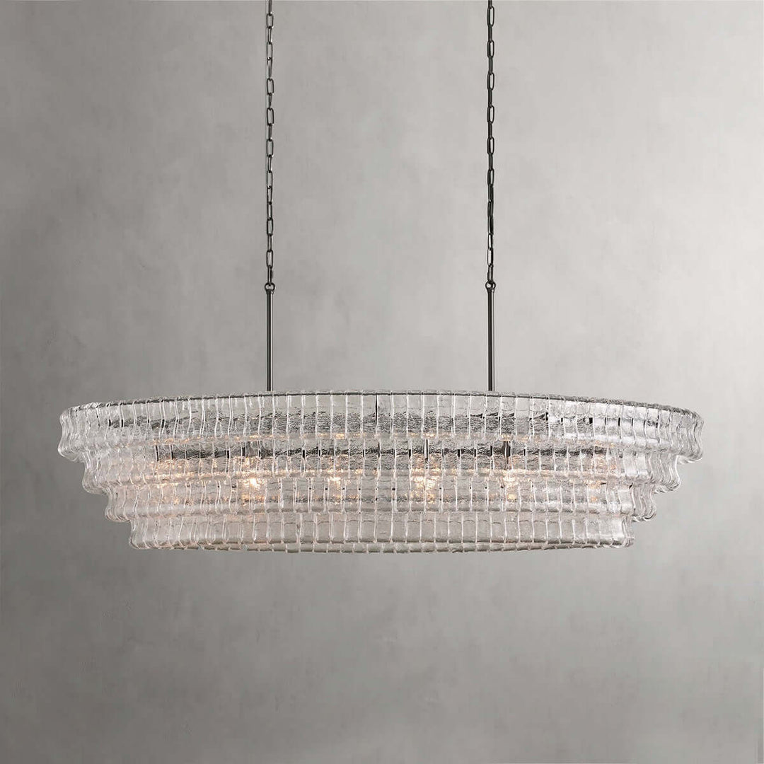 Close front view of a linear clear glass chandelier with black chains and warm bulbs