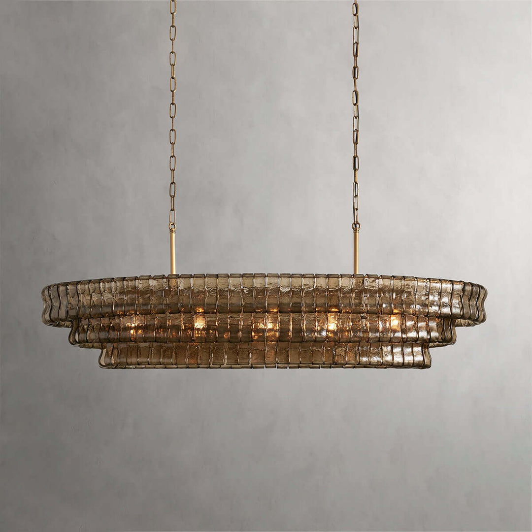 Linear smoky glass chandelier with two gold chains and warm bulbs on a gray background
