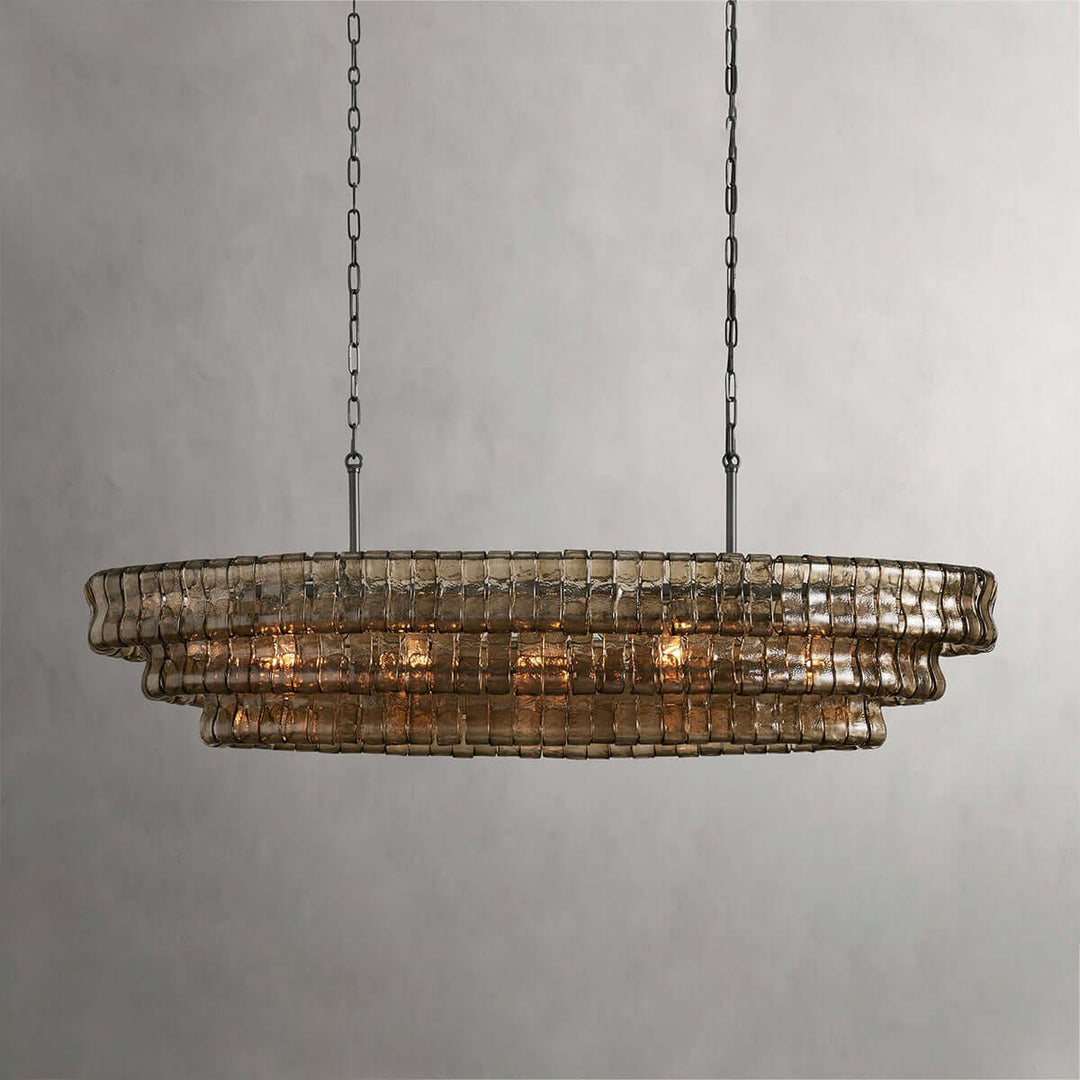 Linear smoky glass chandelier with two black chains and warm bulbs on a gray background