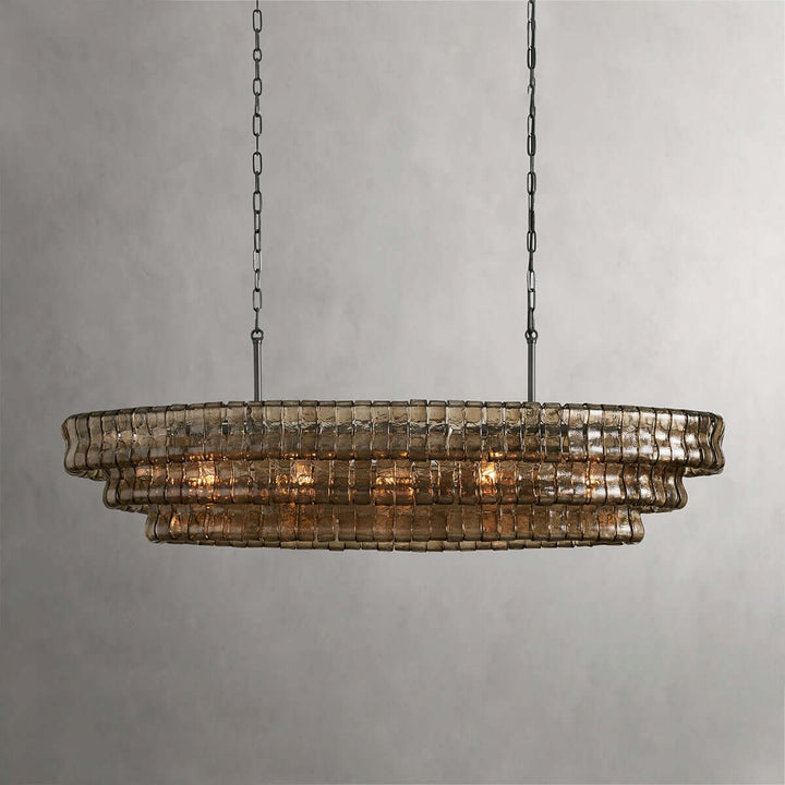 Linear smoky glass chandelier with two black chains and warm bulbs on a gray background