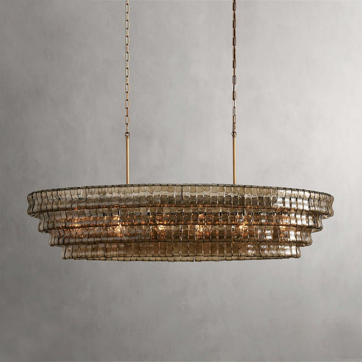 Close front view of a linear smoky glass chandelier with gold chains and warm bulbs