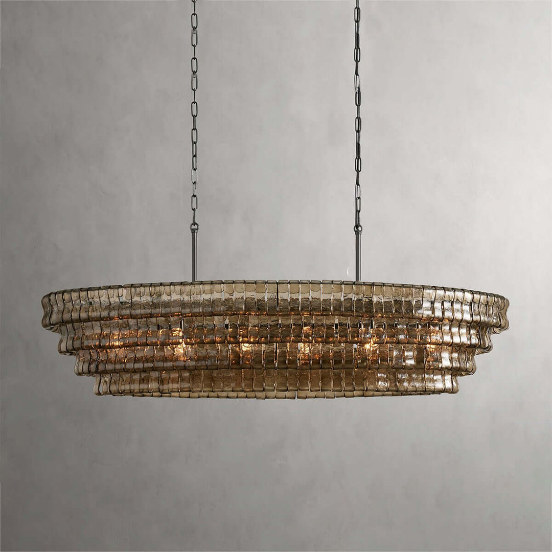 Close front view of a linear smoky glass chandelier with black chains and warm bulbs